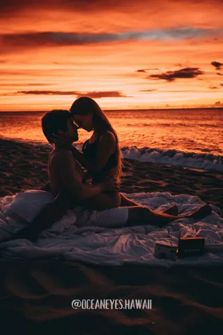 Couple embracing on a beach blanket at sunset in Hawaii