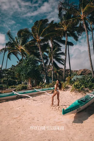 Woman on a beach with palm trees and outrigger canoes in Hawaii