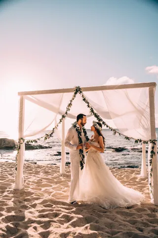Bride and groom under a beach wedding arch in Hawaii