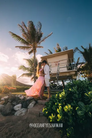 Couple kissing by a lifeguard tower at sunset in Hawaii