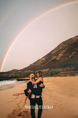 Couple on the beach under a rainbow in Hawaii