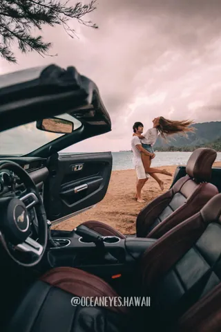 Couple dancing on the beach beside a convertible in Hawaii