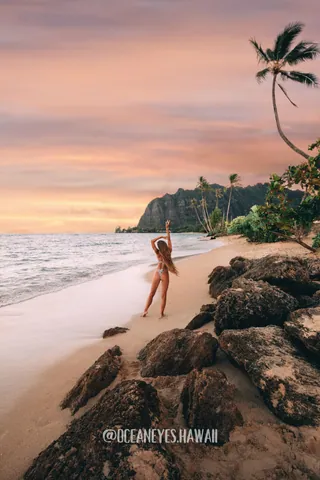 Woman on a beach with palm trees at sunset in Hawaii