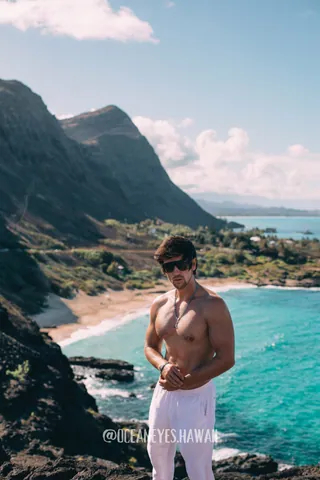 Man in white pants above a turquoise bay in Hawaii