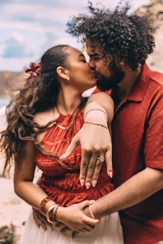Just-engaged couple kissing and showing the ring in Hawaii