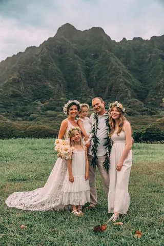 Wedding family photo on a green field with mountains in Hawaii
