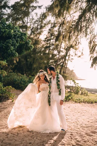 Bride and groom with leis on the beach in Hawaii
