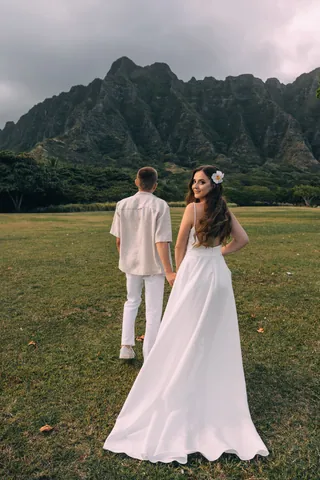 Bride and groom walking toward the mountains in Hawaii