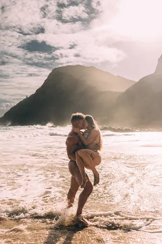 Couple embracing in the surf after a proposal in Hawaii