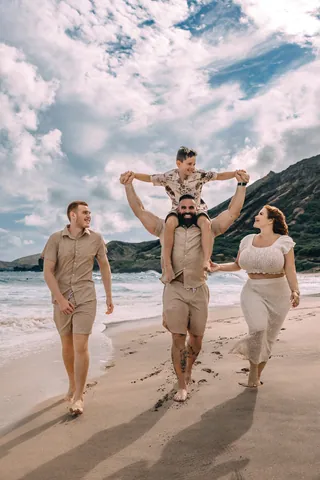 Family on the beach with a child on dad's shoulders in Hawaii